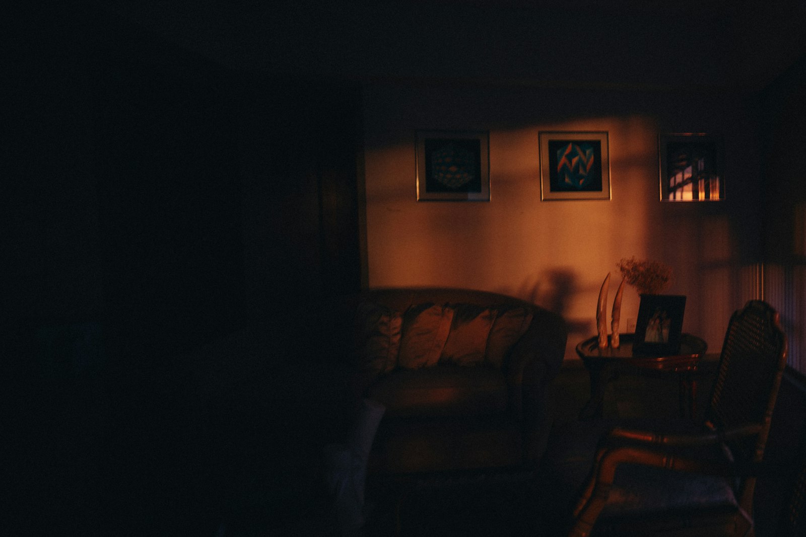 Dæmpet oplyst stue om aftenen med indrammet kunst på væggen og varmt lys fra en lampe